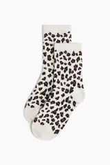 Pack de siete pares de medias de caña media, con diseños variados: dos pares lisos en color crema y blanco, un par negro liso, y cuatro pares con estampado de leopardo en diferentes combinaciones de colores.