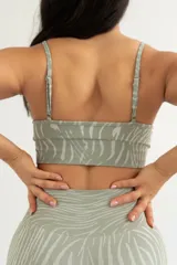 Conjunto deportivo verde con estampado de líneas onduladas, compuesto por un top con tirantes finos y un short ajustado de tiro alto.