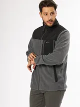 Campera gris de micropolar con paneles negros en la parte superior y cuello alto. Tiene cierre frontal, bolsillos laterales con cierre y logo de la marca bordado en el pecho.