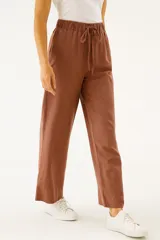 Pantalón de lino color beige, de corte ancho y tiro alto, con bolsillos laterales y cintura elastizada con cordón ajustable.