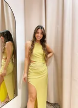 Vestido largo color dorado de lurex, con un hombro descubierto, corte en la cintura y falda con frunces y abertura lateral.