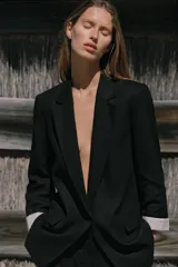 Blazer negro de lino con cuello solapa y escote pico. Manga larga con hombreras y puños con vuelta estampada a rayas. Bolsillos con solapa en el delantero, forro interior y cierre frontal con botón.
