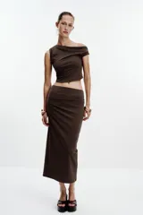 Falda midi color crema, de tiro alto con cintura elástica y detalle de pliegues laterales.