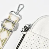 Porta celular blanco de cuero sintético con textura perforada, cierre superior con cremallera y correa de tela estampada ajustable y desmontable.