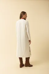 Vestido midi blanco de manga larga, con cuello redondo, bolsillo en el pecho y costuras a la vista.