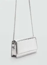Bolso pequeño plateado con efecto piel y textura. Tiene bandolera y cierre de solapa con botón magnético.