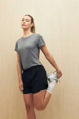 Short deportivo gris oscuro de tejido liviano y elástico, con cintura elastizada, aberturas laterales y calce práctico.