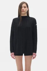 Sweater tejido negro con cuello alto tipo polera, corte oversized y aberturas laterales.