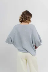 Sweater color crudo de tejido liviano con textura semi traslúcida, escote redondo y mangas amplias estilo murciélago.