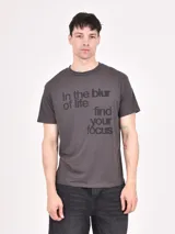 Remera gris oscuro con estampado frontal con la frase "In the blur of life find your focus".