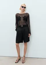 Jersey de punto calado negro con cuello barco y detalles florales bordados.