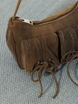 Cartera tipo bandolera color gris oscuro, realizada en cuero ovino, con cierre metálico y forro de poliéster jacquard. Tiene doble bolsillo frontal con cierre imantado y apliques metálicos níquel. Incluye correa corta de cuero para usar al hombro.