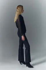 Pantalón jean de tiro medio, confeccionado en denim azul con coating negro que le da apariencia de cuero. Es ajustado en la cintura y levemente acampanado desde la cadera al ruedo.