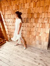 Vestido tejido color blanco con hilo metalizado, corte oversized, mangas cortas y flecos en el ruedo.