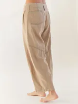 Pantalón largo color beige, tipo baggy, con costuras en verde y etiqueta turquesa en la parte trasera.