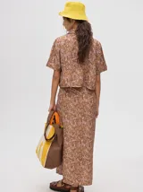 Falda midi marrón con estampado floral en tonos lila, abertura lateral y tiras ajustables.