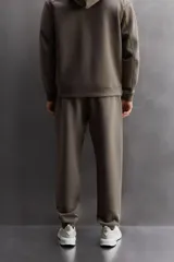Pantalón jogger color marrón oscuro, corte regular fit, confeccionado en tejido técnico compacto de algodón con elasticidad. Cuenta con cintura elástica ajustable con cordón, bolsillos frontales y bolsillo lateral con cierre de cremallera.