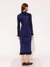 Vestido midi ajustado al cuerpo, de punto calado con estampado floral en azul y negro, cuello alto y volados en puños y ruedo.