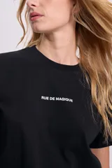 Remera negra de corte recto con estampa frontal con la frase "Rue de Magique" en letras blancas.