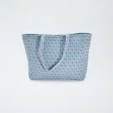 Bolso shopper acolchado de tela celeste con estampado de flores rosas y azules.