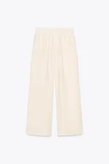 Pantalón de tiro alto color crudo, con cintura elástica, bolsillos delanteros y pernera ancha.