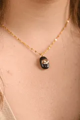 Collar con cadena dorada y dije ovalado de piedra ónix negra con un ojo turco dorado con un cristal en el centro.
