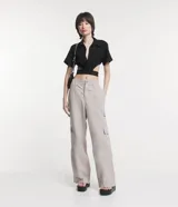 Camisa corta negra con cuello camisero, mangas cortas y aberturas laterales con elástico con letras blancas.
