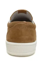 Zapato slip-on color marrón con capellada de cuero sintético microperforado, elástico lateral y suela blanca.