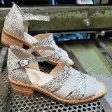 Sandalias de cuero color gris claro con textura de piel de reptil, con puntera descubierta, talón cubierto y tira con hebilla al tobillo.