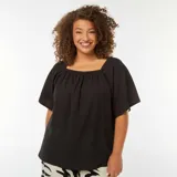 Blusa negra de punto gofrado con cuello bardot y mangas cortas amplias.