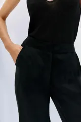 Pantalón palazzo negro de tiro alto, confeccionado en cupro y viscosa. Cuenta con bolsillos diagonales laterales, bolsillos ojal falsos en la espalda y cierre lateral invisible.