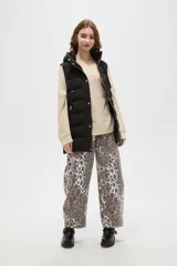 Chaleco puffer negro con capucha ajustable, cierre frontal con botones a presión y bolsillos laterales con cierre.