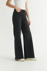 Pantalón jean negro de corte holgado, levemente ajustado en cintura y cadera, con pierna ancha y ruedo desflecado.