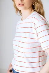 Remera blanca con rayas horizontales finas color rojo.