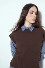 Chaleco tejido sin mangas de color negro, con cuello redondo y diseño de textura sutil. Presenta un corte recto con terminaciones acanaladas en el ruedo y hombros levemente estructurados.