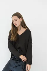 Sweater de punto negro con cuello en V y diseño holgado, ideal para combinar con distintas prendas.