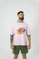 Remera oversize rosa con cuello y mangas con ribete verde. Estampado frontal con diseño de frutas y texto.