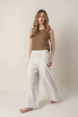 Pantalón ancho de lino color crudo con rayas verticales en tonos celeste, naranja y rosa. Tiene bolsillos laterales y cierre con botones a la vista en el lateral.