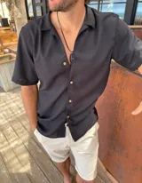Camisa negra de fibrana con cuello solapa, manga corta y cierre frontal con botones de madera.
