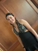 Vestido corto de lentejuelas color verde oliva, con escote en V, breteles finos cruzados en la espalda, cut-outs laterales y volado en el ruedo.