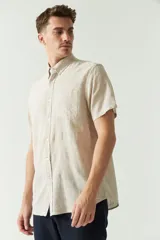 Camisa de manga corta color beige claro, confeccionada en lino y algodón, con cuello abotonado, bolsillo en el pecho y logo bordado. Corte semi slim.