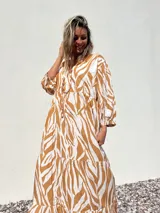 Vestido largo tipo túnica con estampado de cebra en tonos beige y crudo, con cuello en V y mangas 3/4.