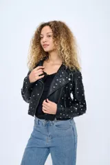 Chaqueta corta estilo motoquera de cuero sintético negro, con cuello solapa y cierre cruzado con cremallera. Decorada con tachas plateadas en solapas, hombros y mangas.