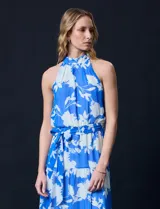 Vestido largo de gasa con estampado floral en tonos celeste y blanco. Tiene escote halter, cintura elastizada con lazo de ajuste, abertura en la espalda con botones y forro interno.