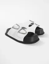 Sandalias blancas de cuero sintético con suela negra y hebilla plateada.