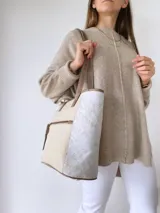 Bolso tipo tote bag color beige con laterales estampados y detalles en cuero marrón.
