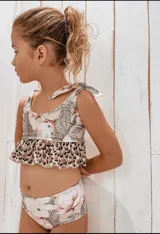 Conjunto de bikini para niña con estampado floral y animal print. El top tiene tirantes con lazos y volantes en la parte inferior.