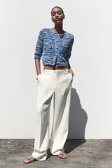 Chaqueta de punto azul y blanco con cuello redondo y manga francesa. Tiene bolsillos delanteros de plastrón y cierre frontal con botones a tono.