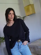 Remera negra de manga larga con cuello redondo. Jeans de tiro alto color celeste con cinturón con hebilla dorada. 