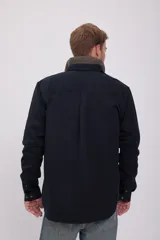 Camisa negra de manga larga con cuello clásico y cierre frontal con botones. Tiene un bolsillo de parche en el pecho izquierdo.